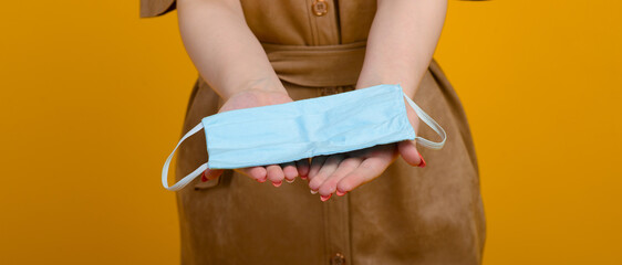 Image of female hands with blue mask on yellow background Healthcare Covid 19 outbreak contamination