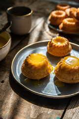 Shaped mini bundt cakes filled with lemon curd and cup of coffee on old wooden table.
