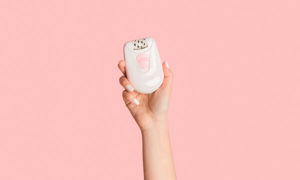 Unrecognizable millennial girl showing modern electric epilator on pink background