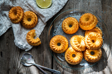 Homemade shaped mini bundt cakes on glass plate on old wooden table.