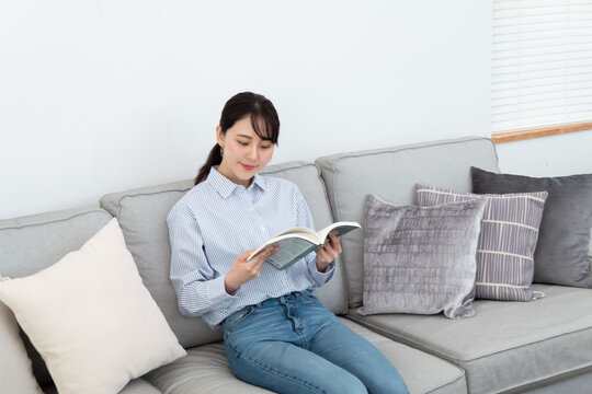 ソファに座って本を読んでいる女性