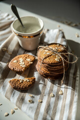 Homemade oatmeal cookies and bowls with ingredients on white kitchen table.