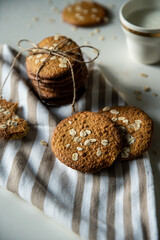 Homemade oatmeal cookies and bowls with ingredients on white kitchen table.