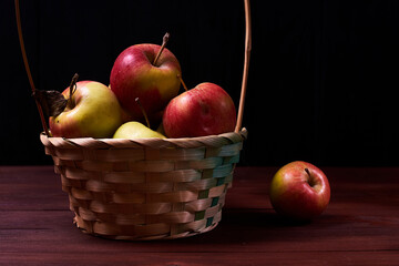 Fresh apples in a basket on a wooden background.