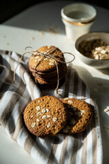 Homemade oatmeal cookies and bowls with ingredients on white kitchen table.