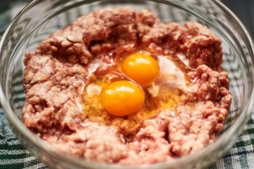 Minced meat with raw egg in a plate. Cooking meat products.