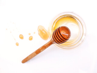 Top view of honey stick in empty honey glass jar with stain of honey isolated on white background.