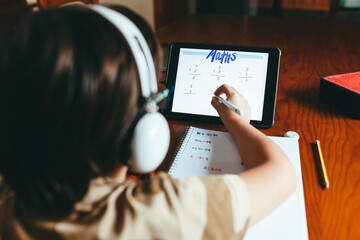 Boy doing his math homework. Adding on your tablet with a touch pen. - Powered by Adobe