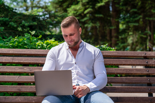 a man of European appearance works remotely using a laptop while he is in the park