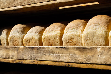 Showcase of the food market with fresh rye bread, close-up. Wooden shelves with bread in the shape of a brick. Delicious, Golden, crunchy bread brought from the bakery early in the morning
