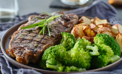 Selbstklebende Fototapeten Steakhouse grilled new york strip steak with rosemary and vegetables  © Joshua Resnick