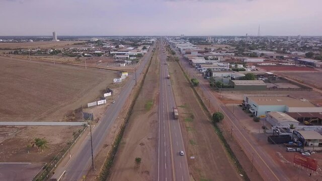Drone aerial view of cars and trucks driving on BR 163 road and Sinop city skyline in a sunny summer day. Mato Grosso, Brazil. Concept of transport, travel, transportation, logistics, economy.