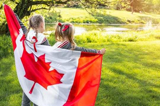 Happy Canda Day Celebrtation concept. Two cute female kids with Canadian flag. Back view.