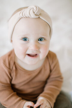 Closeup of baby girl smiling at the camera with big blue eyes
