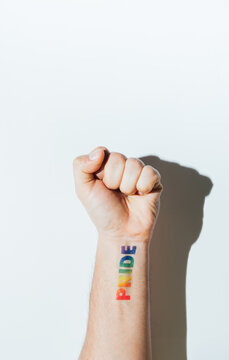 Gay guy's hand with a tattoo that says pride and nail polish.