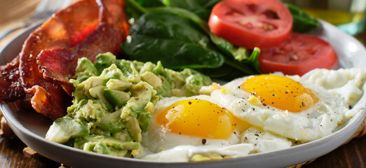 keto breakfast plate with eggs bacon and mashed avocado
