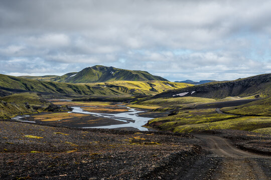 Black dirt road winding through green landscape in Iceland
