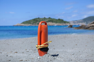 A red life buoy of a lifeguard stuck in the sand on the beach. Lifeguard material for buoyancy.