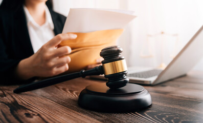 Justice and law concept.Male judge in a courtroom with the gavel, working with, computer and docking keyboard, eyeglasses, on table in morning light