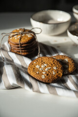 Homemade oatmeal cookies and bowls with ingredients on white kitchen table.