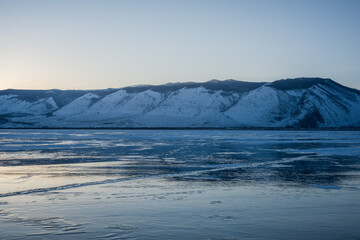 Fototapeta na wymiar Early morning on the ice of lake Baikal against the background of mountains and ice