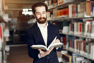 Man in a library. Guy in a black suit. Student with a books.