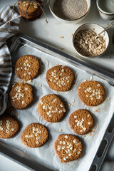 Freshly baked homemade oatmeal cookies on baking tray on white kitchen table.