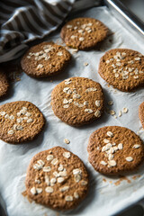 Freshly baked homemade oatmeal cookies on baking tray on white kitchen table.