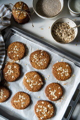 Freshly baked homemade oatmeal cookies on baking tray on white kitchen table.