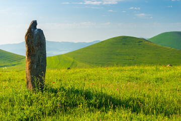 Stone stands in a field, landscape Armenian hills and fields in summer