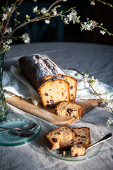 Sliced homemade pound cake with dried berries, vintage glass plates and blooming cherry twigs on linen tablecloth.