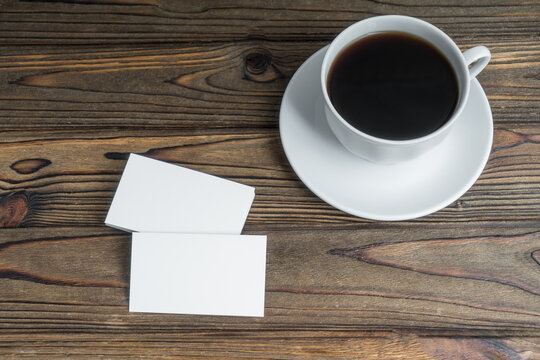 White Clean Business Cards And A Cup Of Coffee On A Wooden Table. Business Concept Idea, Advertising, Negotiations, Coffee Break, Promotion