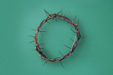 Crown of thorns on green background. Top view. Copy space. Christian Easter concept. Crucifixion of...