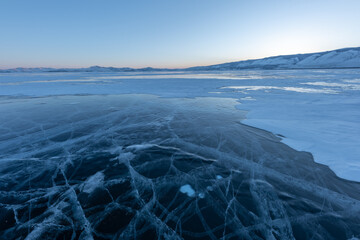 Early morning on the ice of lake Baikal against the background of mountains and ice