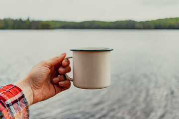 Cup of coffee in hand by lake