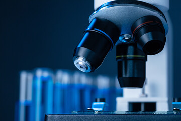 Close up of laboratory microscope with set of test tubes with blue liquid