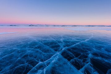 Early morning on the ice of lake Baikal against the background of mountains and ice