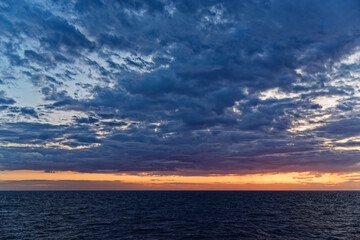 Naklejka na ściany i meble Beautiful scene of colorful cloudy sky above sea during sunset