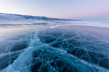 Early morning on the ice of lake Baikal against the background of mountains and ice