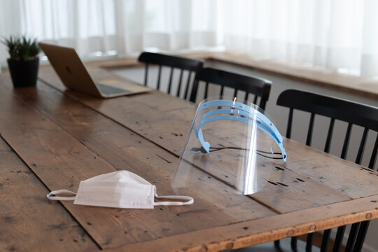 木のテーブルにマスクとフェイスシールドが置いてある