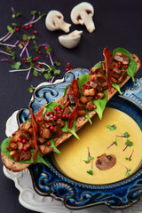 Mushroom cream soup with rye bread bruschetta in a blue ceramic plate. Copy of the space. Macro photo on a dark background. Top view.