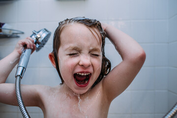 close up of young child singing in shower while washing hair
