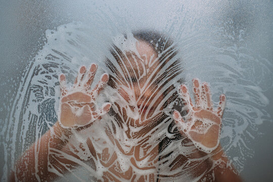 close up of child in shower playing with soap on door