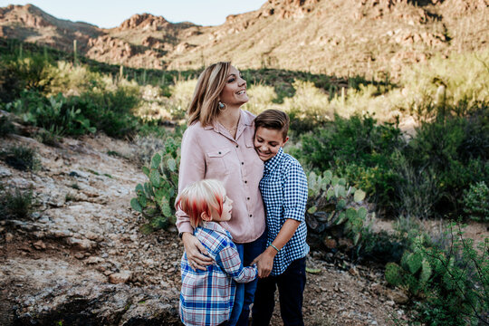 mom smiling and hugging her two non binary children - Powered by Adobe
