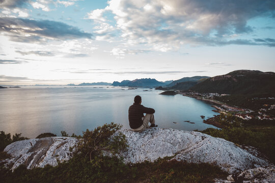 Hiker sitting on a rock looking at sea and islands