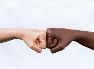 Two hands of different racial colors, punching each other, expressing victory, agreement, partnership. The concept of ending racism - obrazy, fototapety, plakaty