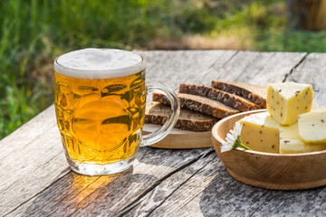 Glass of light beer with cheese and rye bread