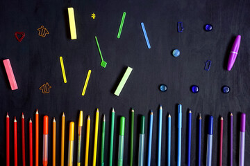 Colorful stationery on black. Flat lay. Row of tools, gradient rainbow colors.