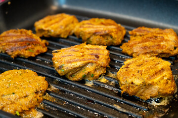 Shallow depth of feild shot mince meat mutton patties keema roasting on a pan with oil bubbling out as they get charred