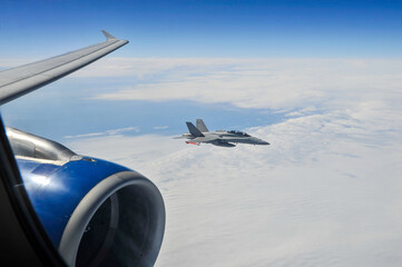 A view from inside passenger jetliner cabin of a military jet fighter escorting commercial aircraft...
